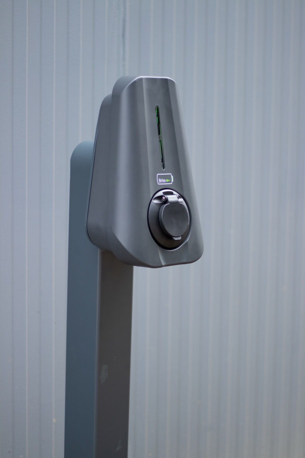 Close-up of a Brim smart charger against grey cladding